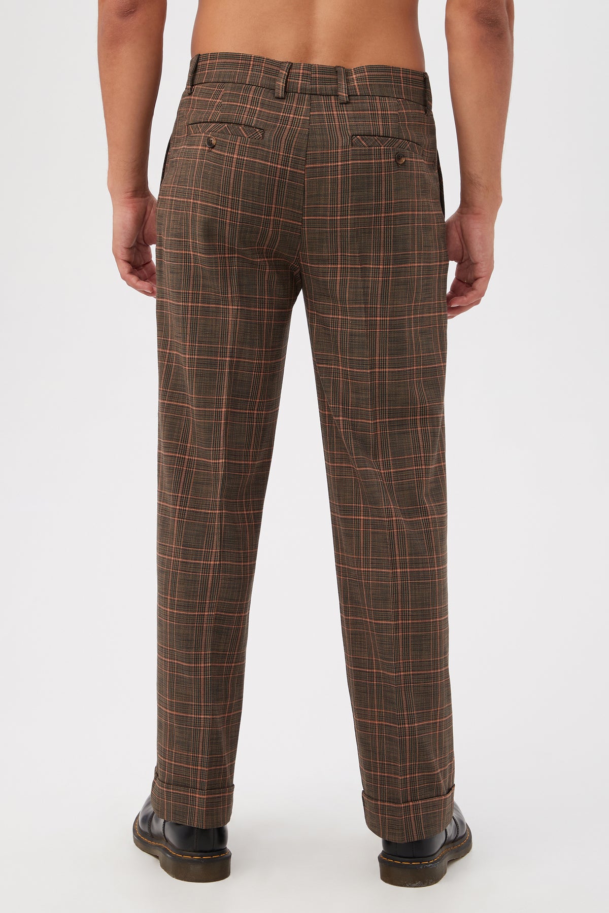 A person faces away from the camera, wearing Genet Wide-Leg Trousers in Chaka Check Plaid and black shoes. Their upper body is bare, set against a plain white background.