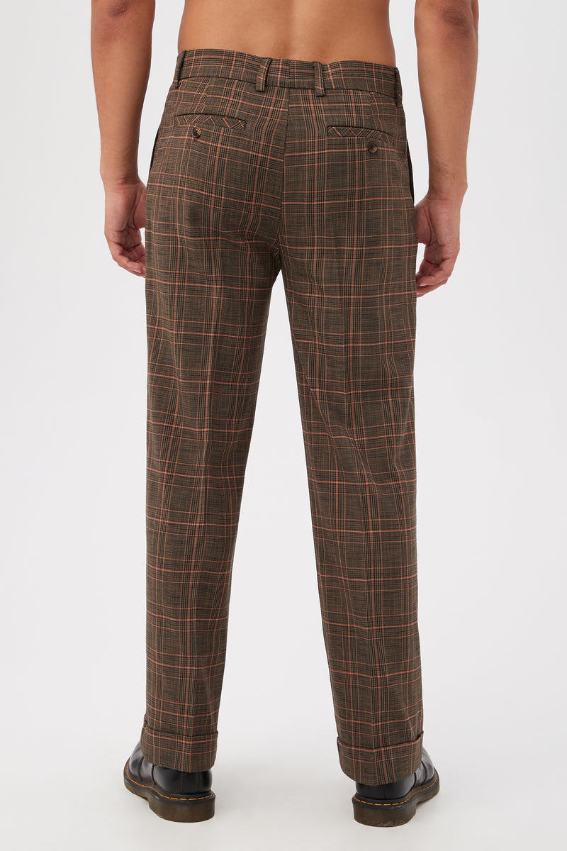 A person faces away from the camera, wearing Genet Wide-Leg Trousers in Chaka Check Plaid and black shoes. Their upper body is bare, set against a plain white background.