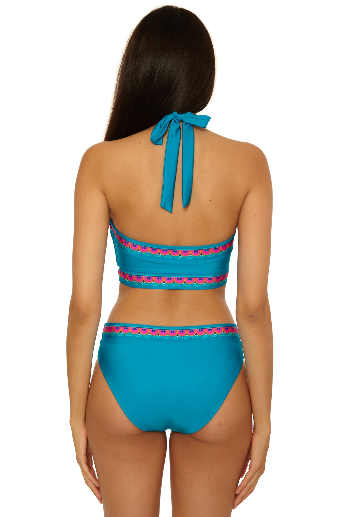 A woman with long dark hair, seen from behind, models the Mykonos Reversible Hi Neck Top—a turquoise halter bikini featuring colorful embroidered bands and a neck tie.