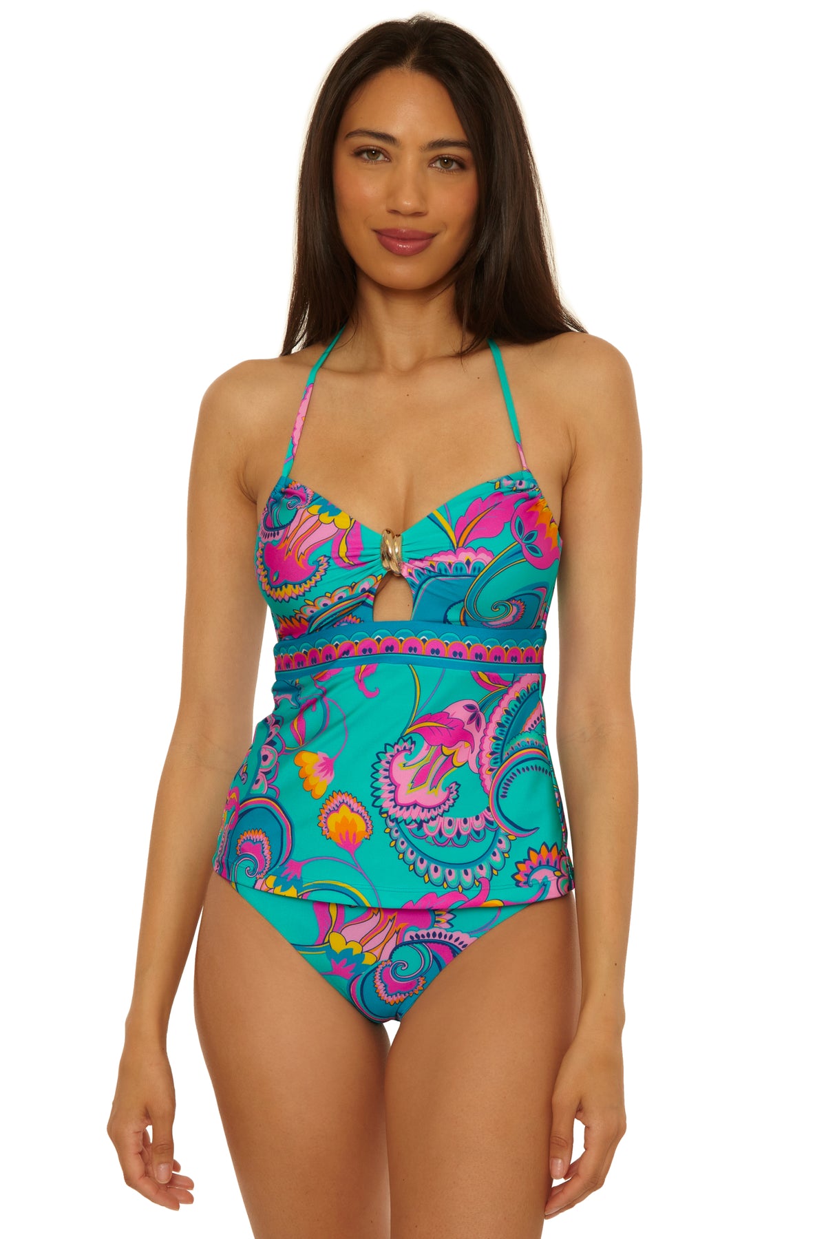 A woman smiles gently against a plain white background, modeling the Mykonos Bandeau Tankini—a colorful one-piece swimsuit with a bold paisley pattern in turquoise, pink, and yellow, featuring a gold accent at the bust.