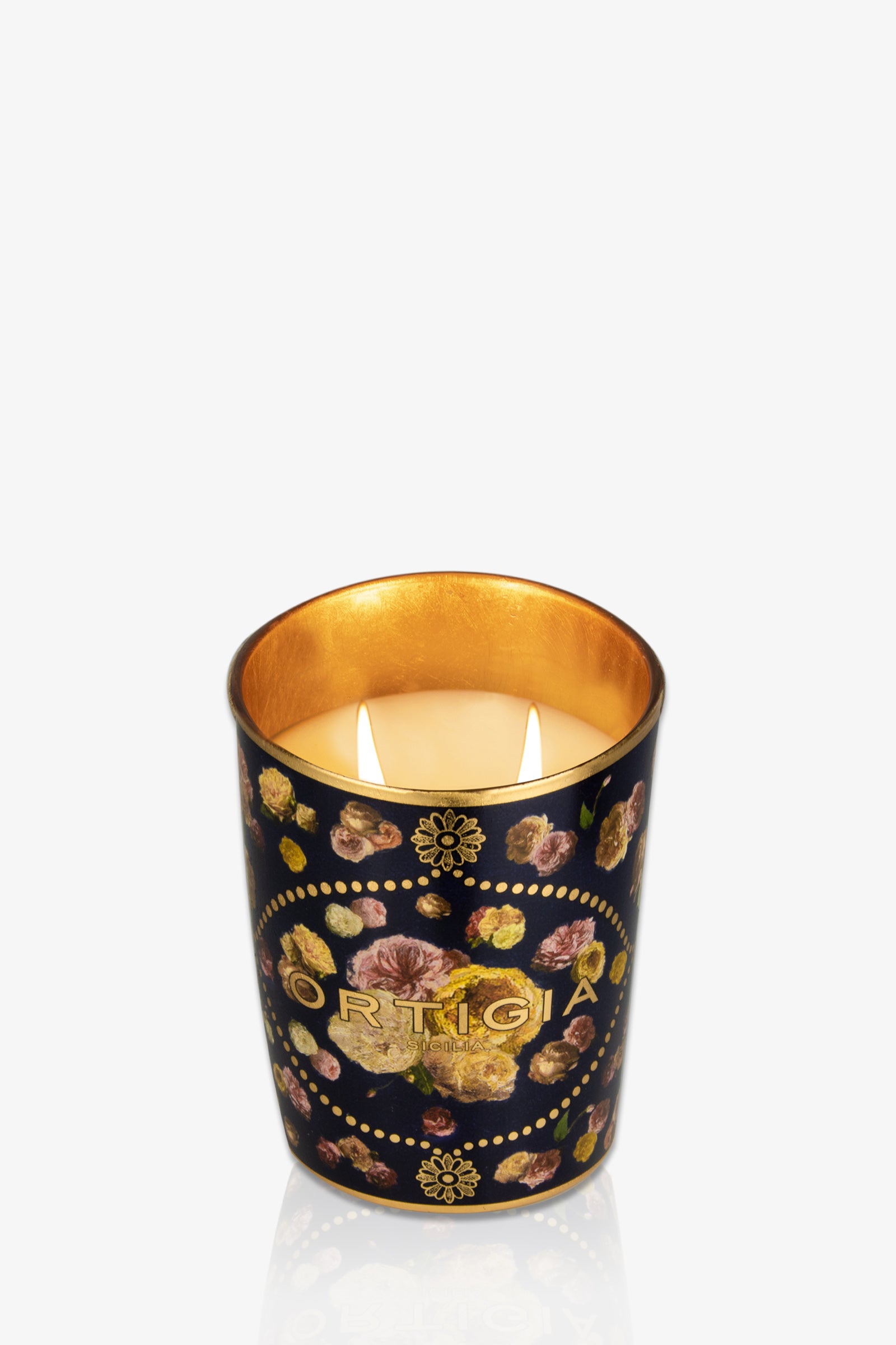The Ortigia Medium Candle is a decorative candle in a black glass holder with gold interior, floral patterns, and “ORTIGIA” in gold letters on the front.