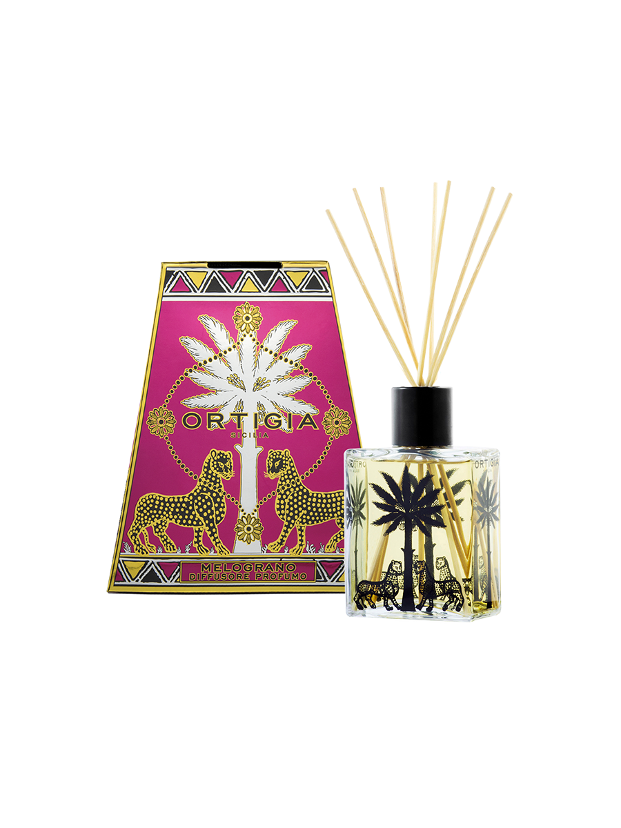 The Ortigia Melograno Diffuser features a red glass bottle with black palm tree and leopard designs, liquid fragrance, reed sticks, and comes in a vibrant pink and gold Ortigia box adorned with palm trees and leopards.