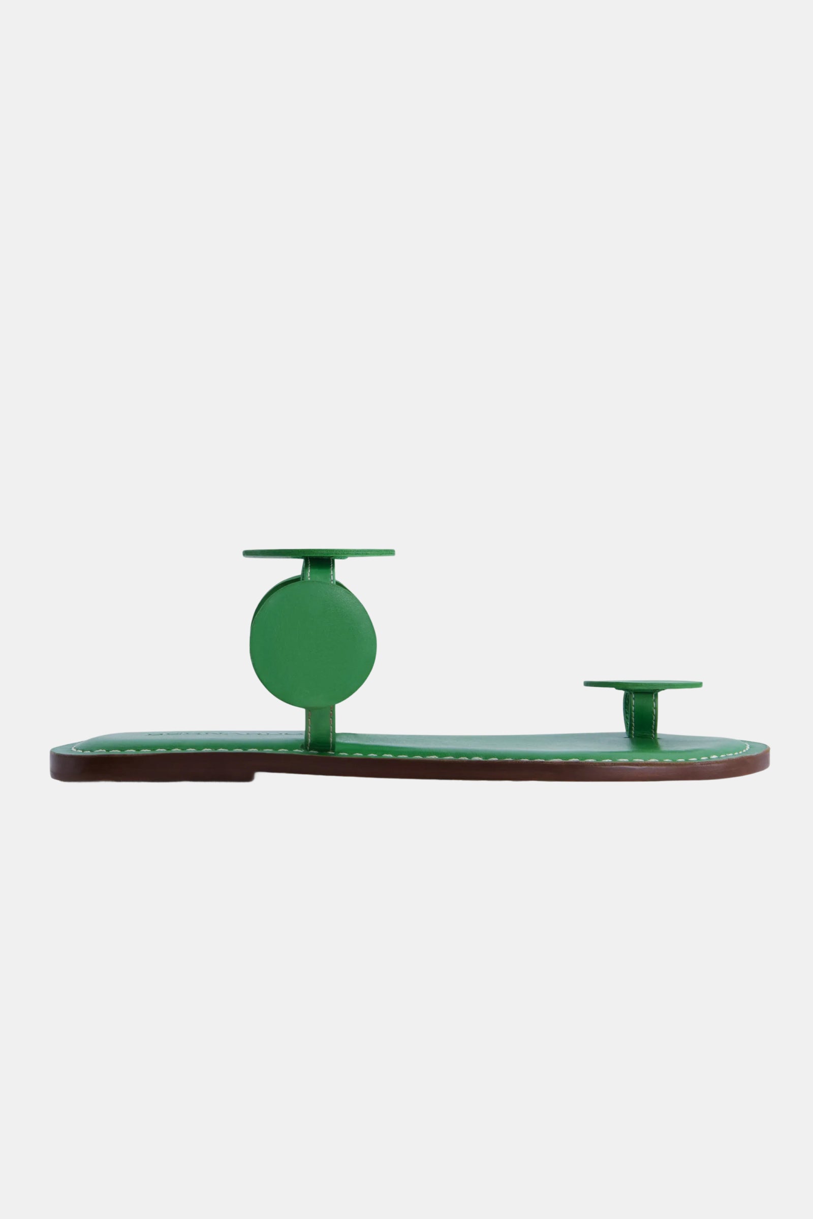 The Bernardo New Moon Sandal is a minimalist green flat with two circular straps—one around the ankle and one at the toe—shown on a plain white background.