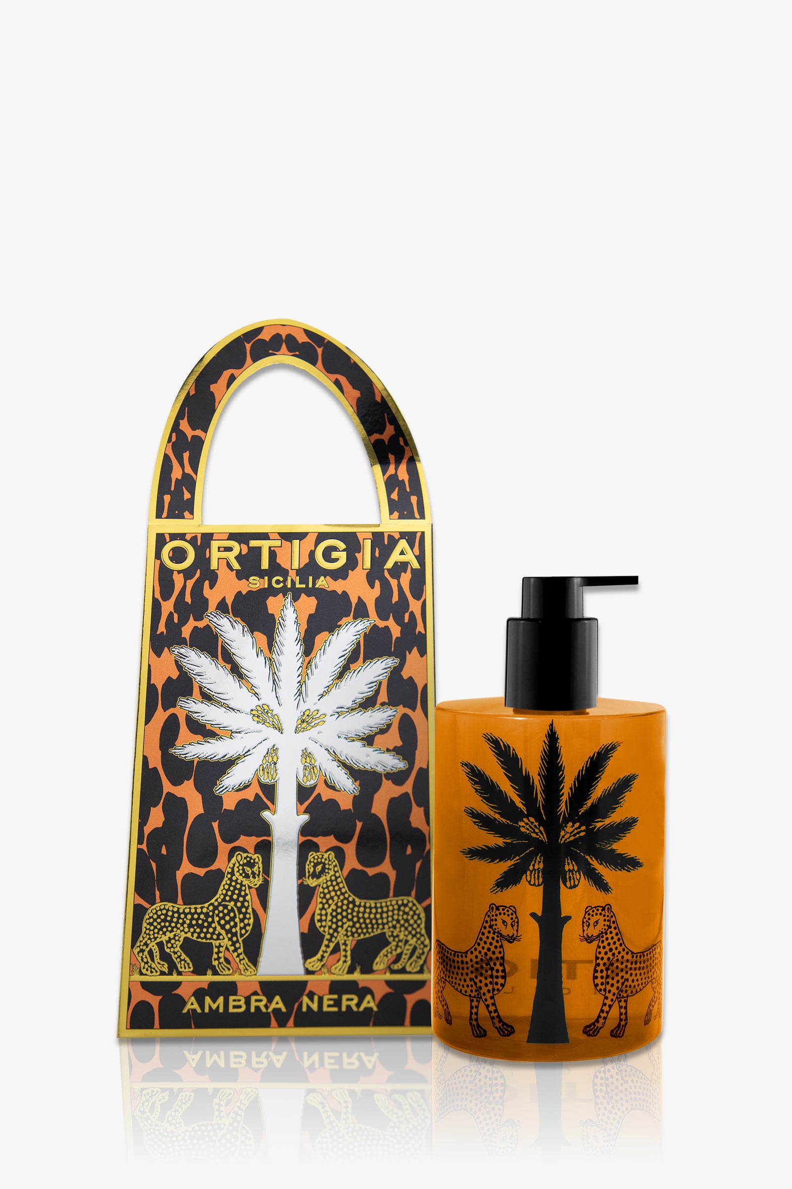 Amber-colored Ortigia Ambra Nera Hand Soap bottle with black pump, adorned with palm tree and leopards, sits beside a matching decorative box featuring a cutout handle, palm tree, and leopard design.
