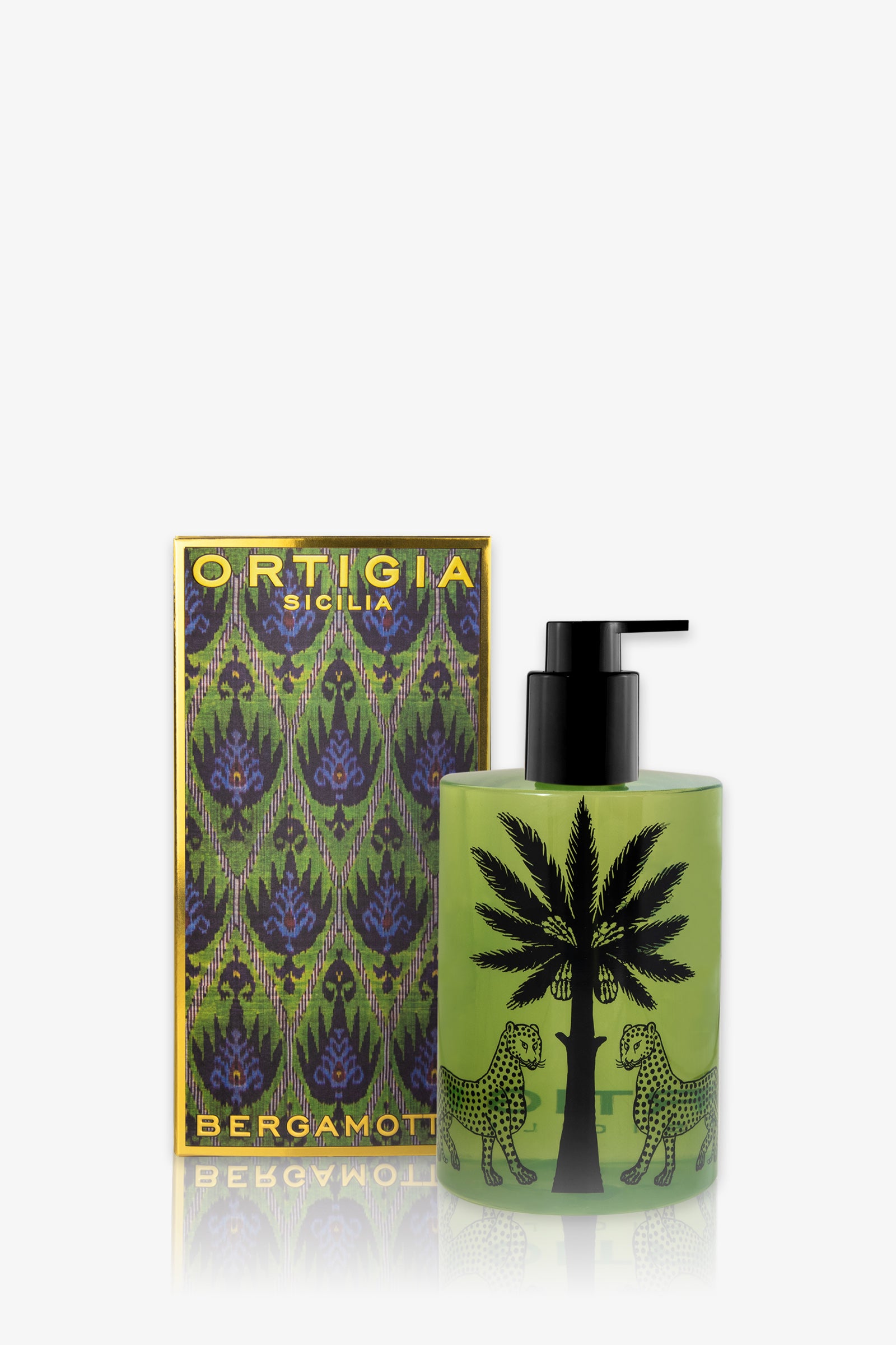A green Ortigia Bergamot Shower Gel bottle with a black pump, featuring two black leopards and a palm tree, is displayed beside its colorful patterned box.