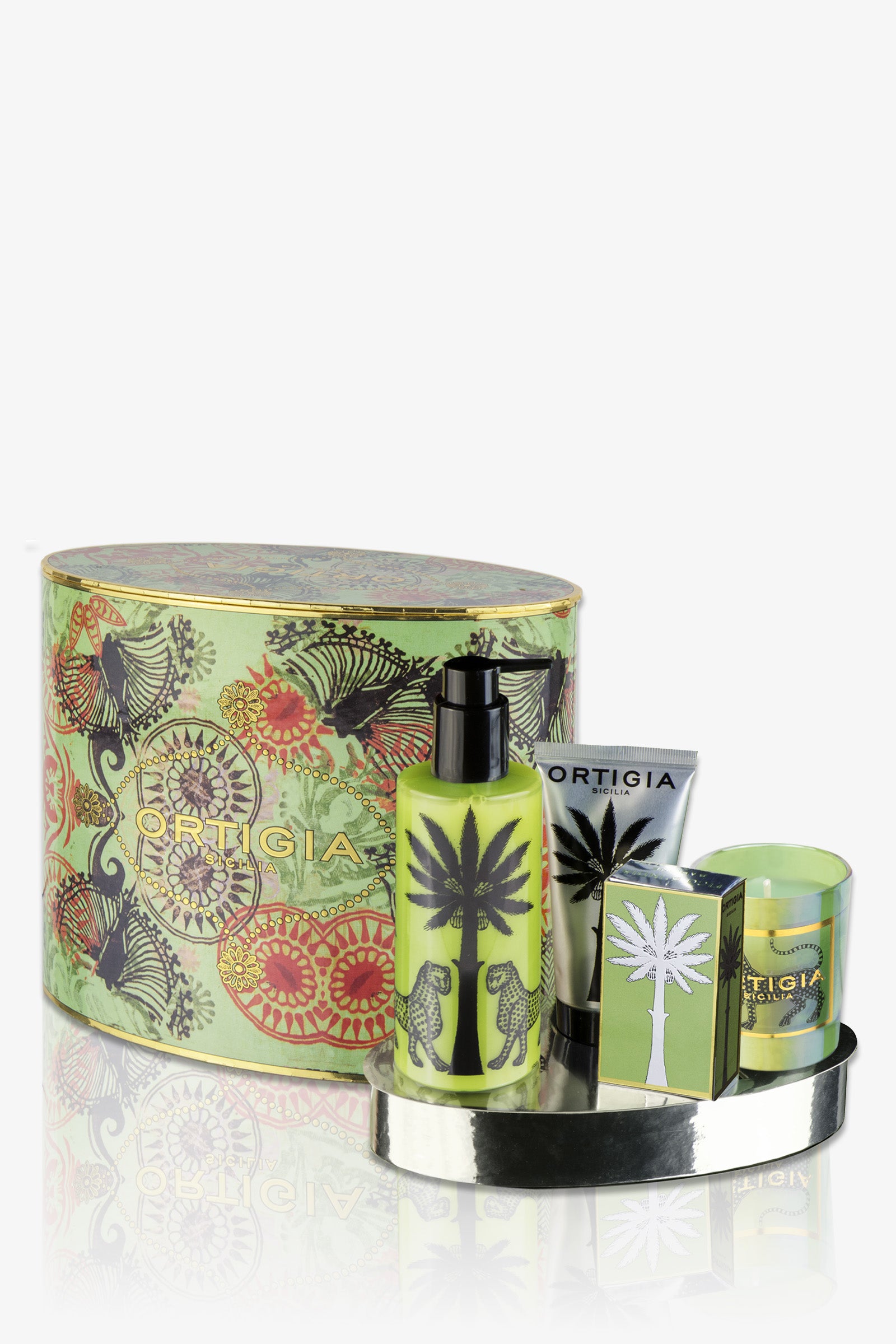 The Ortigia Fico D'India Oval Set features a green patterned box with four products—lotion, tube, soap, and candle—all with palm and animal designs, beautifully arranged on a small silver tray.