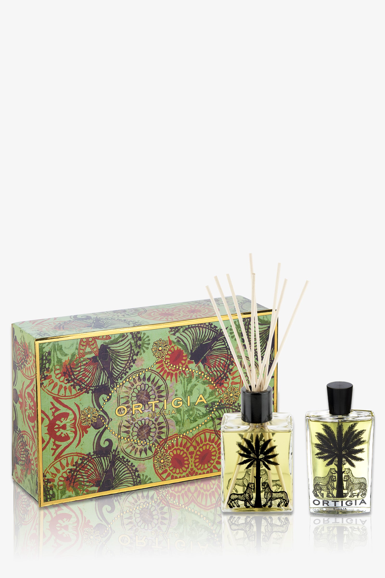 The Ortigia Fico D'India Casa Set in green includes a decorative box, a square glass reed diffuser with a black palm tree design, and a matching bottle of liquid perfume.