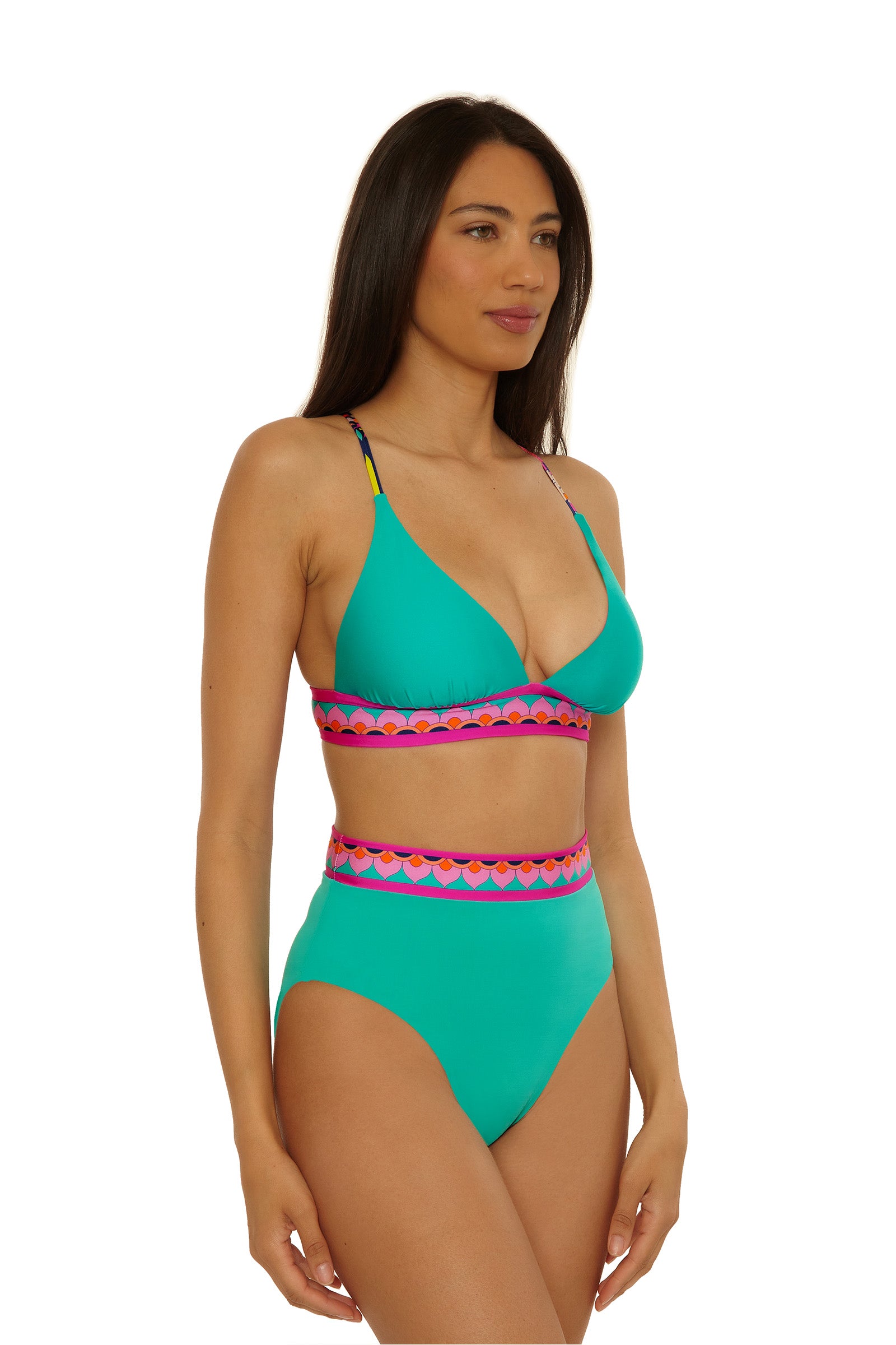 A woman models the Paralia Rev Hi Waist Bottom bikini in turquoise with pink and purple trim, featuring a high-waisted bottom and a halter-style top, standing against a white background.