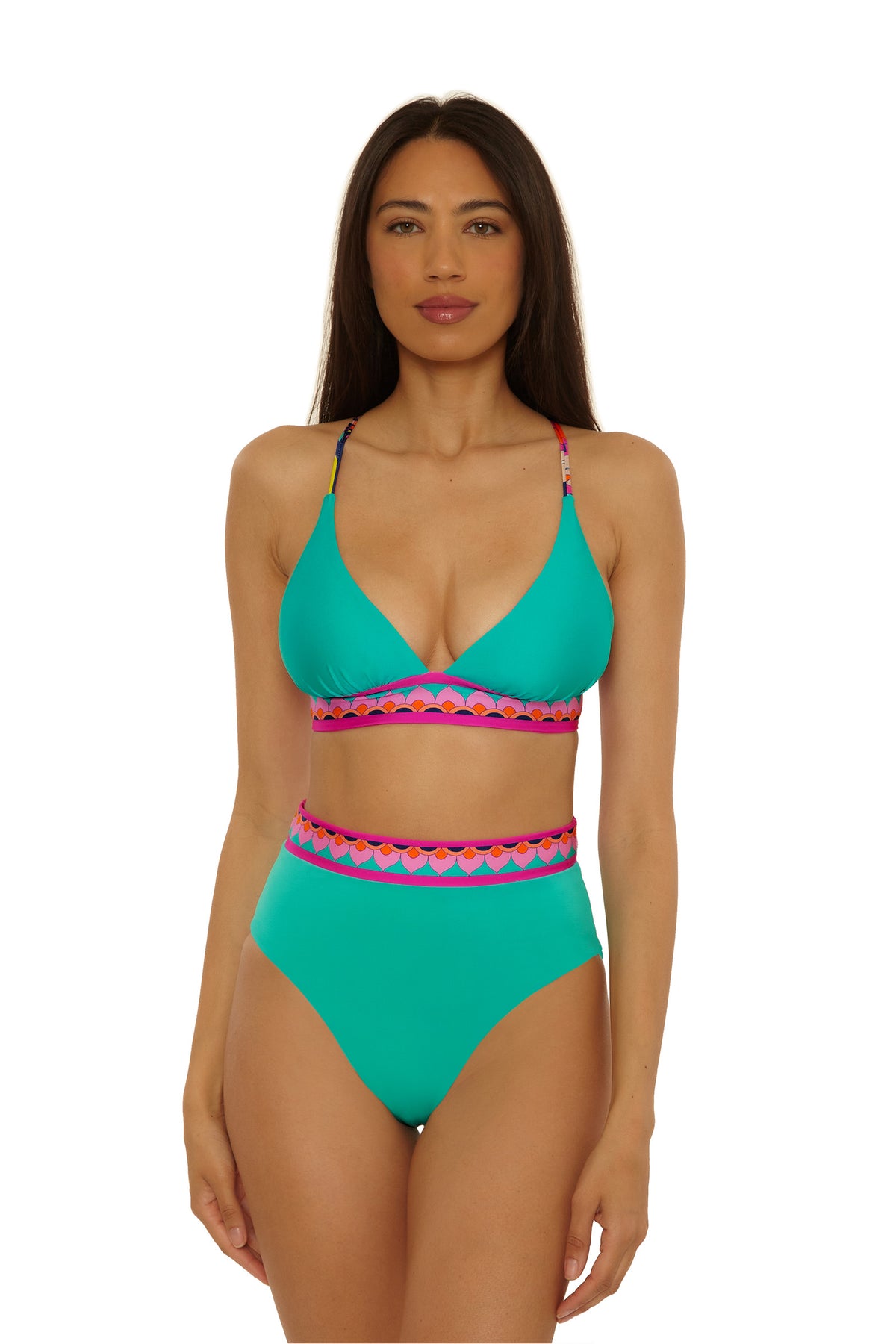 A woman with long brown hair wears the Paralia Rev Hi Waist Bottom bikini in turquoise, featuring pink and orange geometric trim at the waistband and straps. She stands facing forward against a plain white background.