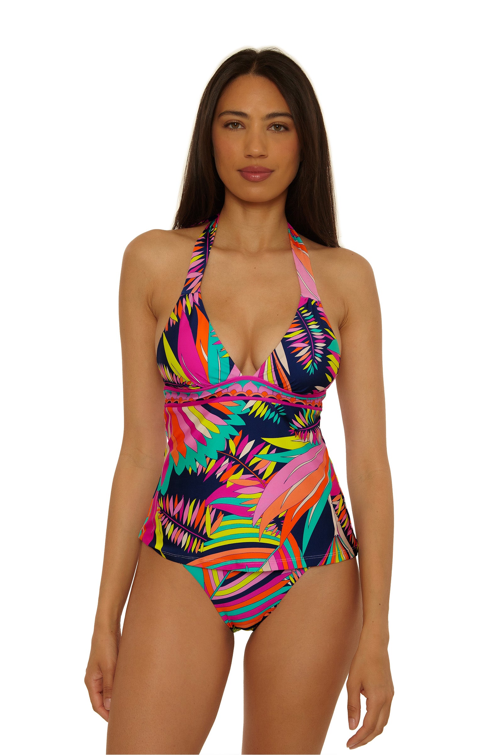A woman models the Paralia Banded Tankini, featuring a colorful tropical print and halter-neck design, standing against a plain white background with a neutral expression.