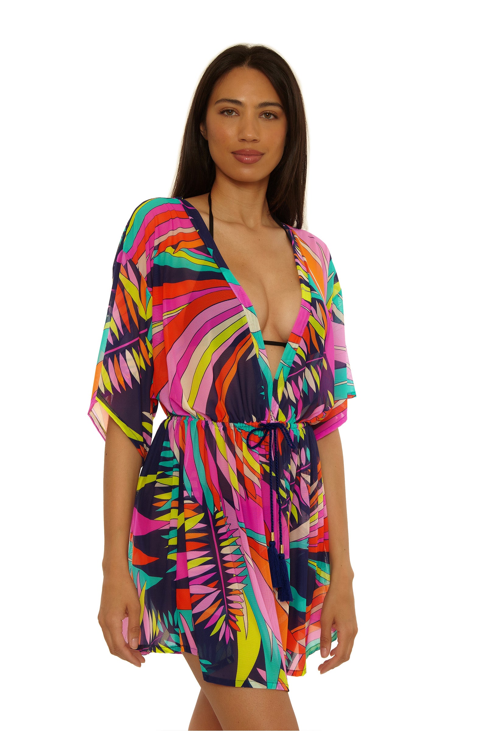 A woman wears the Paralia Mesh Tunic Dress over a bikini, smiling and standing against a white background.