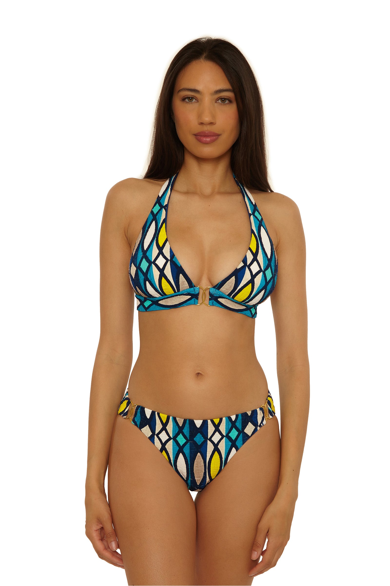 A woman with long brown hair models the Paros Banded Halter Top bikini, featuring blue, yellow, white, and black geometric patterns, standing against a plain white background.