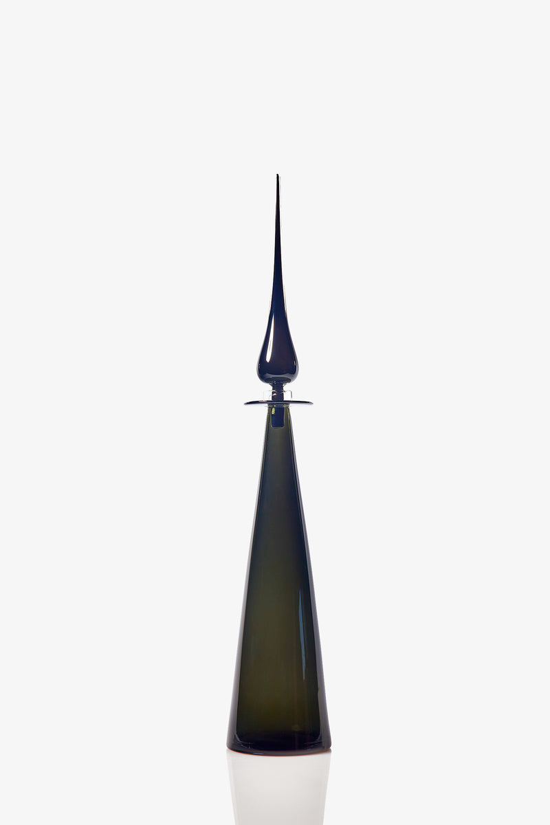 A sleek, modern Petite Straight Cone Decanter in tall, dark green glass with a pointed, elongated stopper stands against a plain white background. The decanter features a reflective surface and minimalist design.