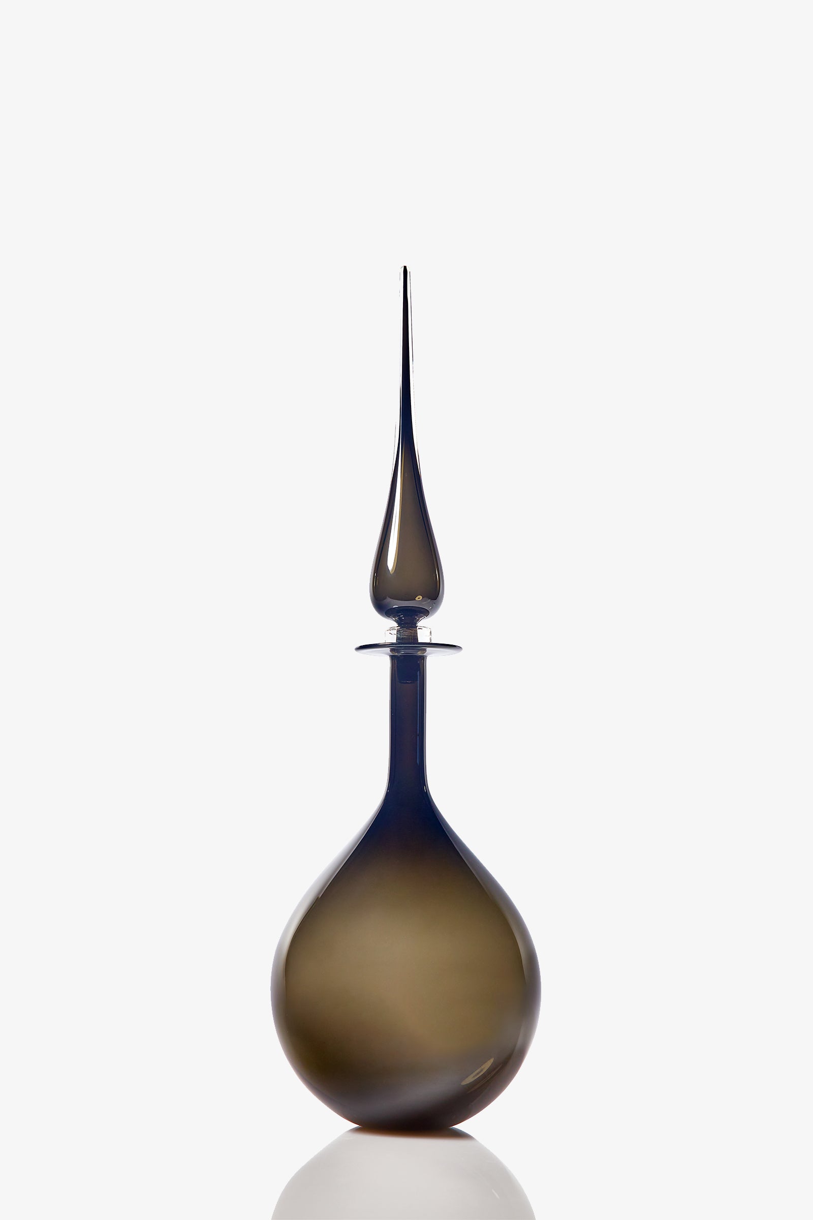 The Petite Tear Drop Decanter features smoky glass with a wide round base and a tall, slender, pointed stopper, shown against a white background.