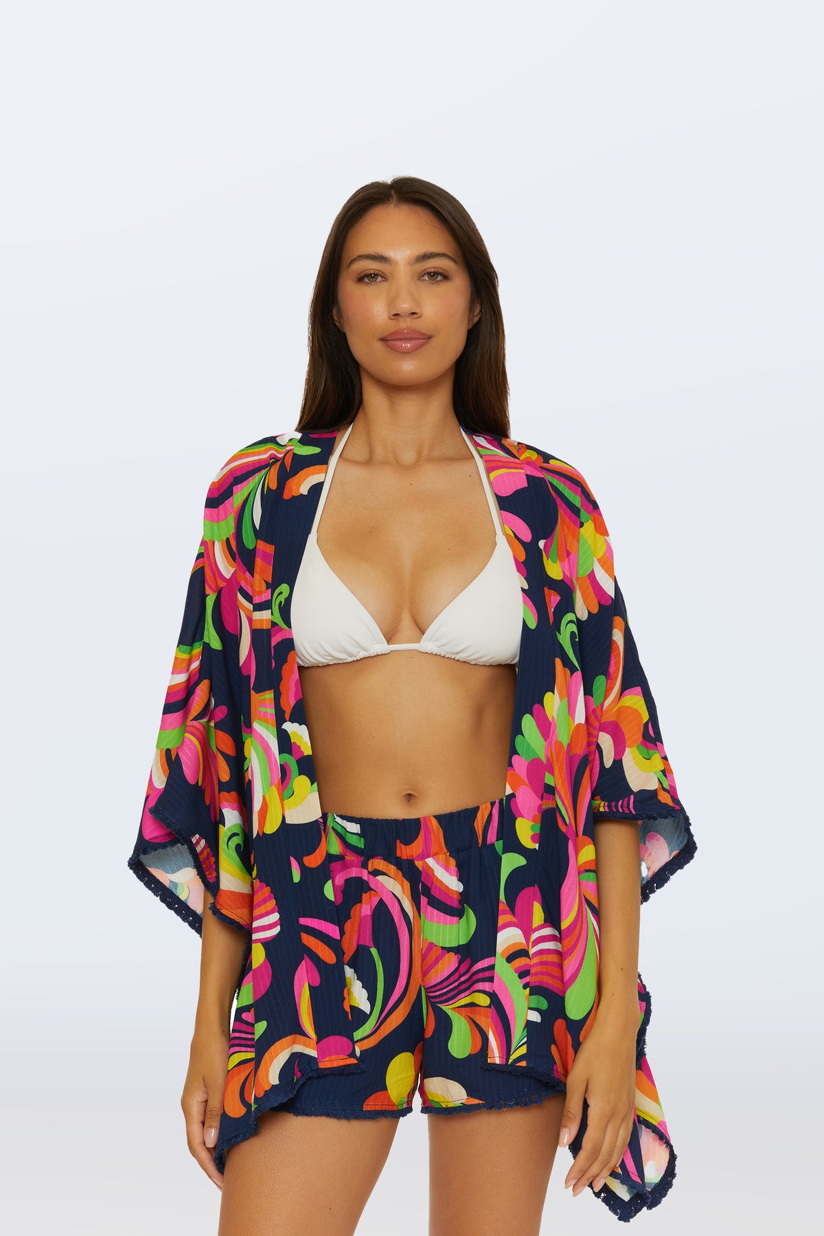 A woman wears the Kimono Swim Cover-Up - Palms Paradise in multi over a white bikini top and shorts, standing against a plain light background.
