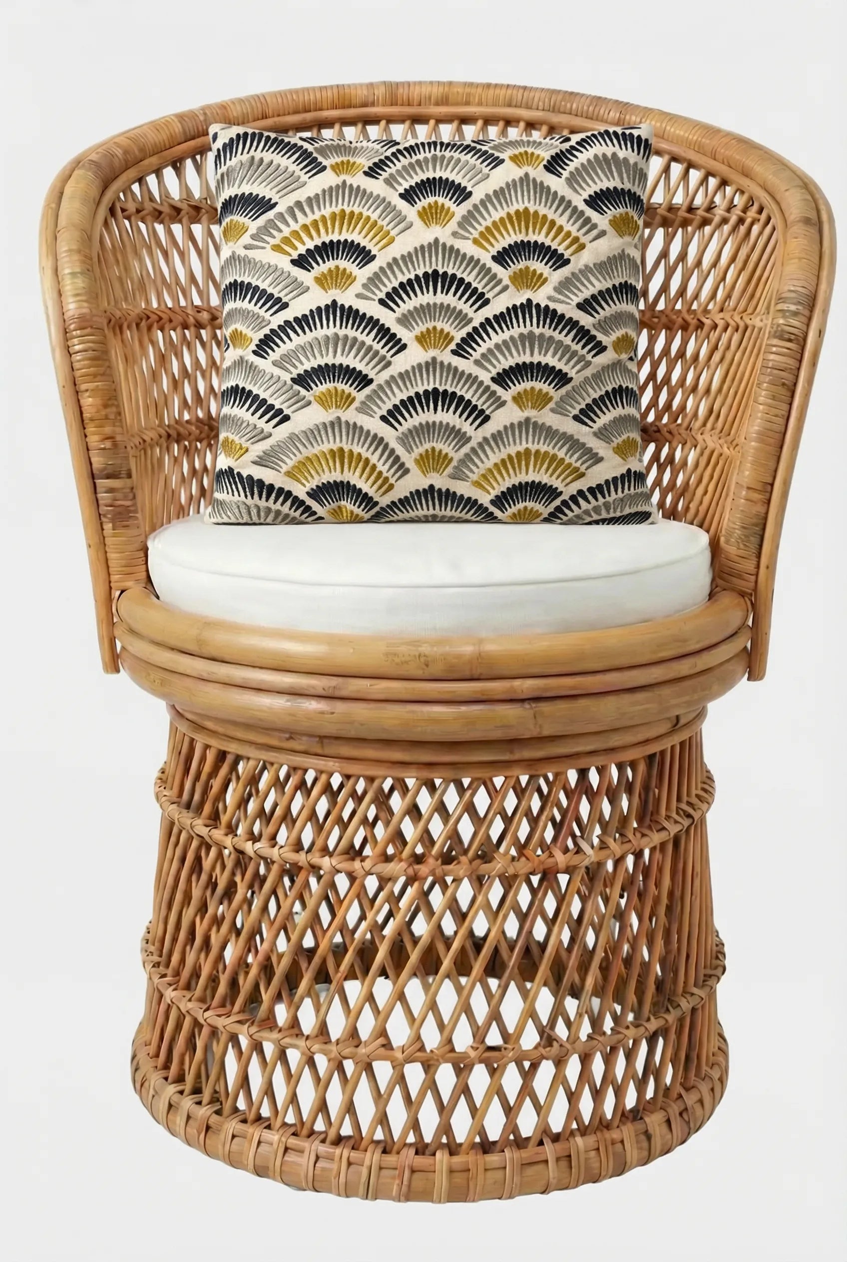A round rattan chair with an open lattice design, a white seat cushion, and the Pasadena Embroidered Throw Pillow featuring a black, gold, and beige geometric fan pattern.