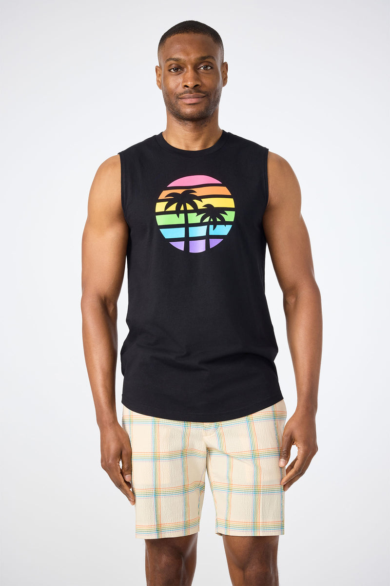 A man faces forward against a white background, wearing the Sleeveless Muscle Tee - Pride in black with a rainbow palm tree graphic and light plaid shorts.
