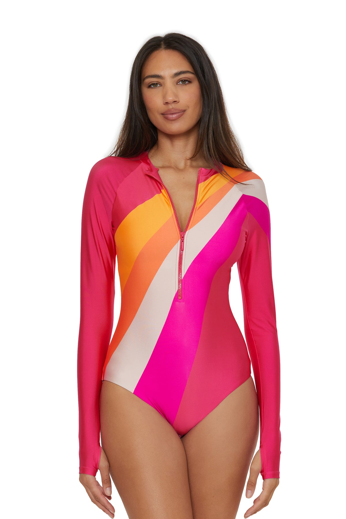 A woman wears the Long-Sleeve Zip-Up Paddlesuit - Sunburst, a colorful one-piece with pink, orange, and white diagonal stripes and a front zipper. She stands against a white background, facing forward.
