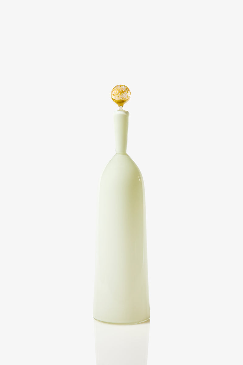The Tall Bottle Carmella Barware features a pale green, smooth, rounded body with a narrow neck and a yellow decorative stopper, displayed against a plain white background.