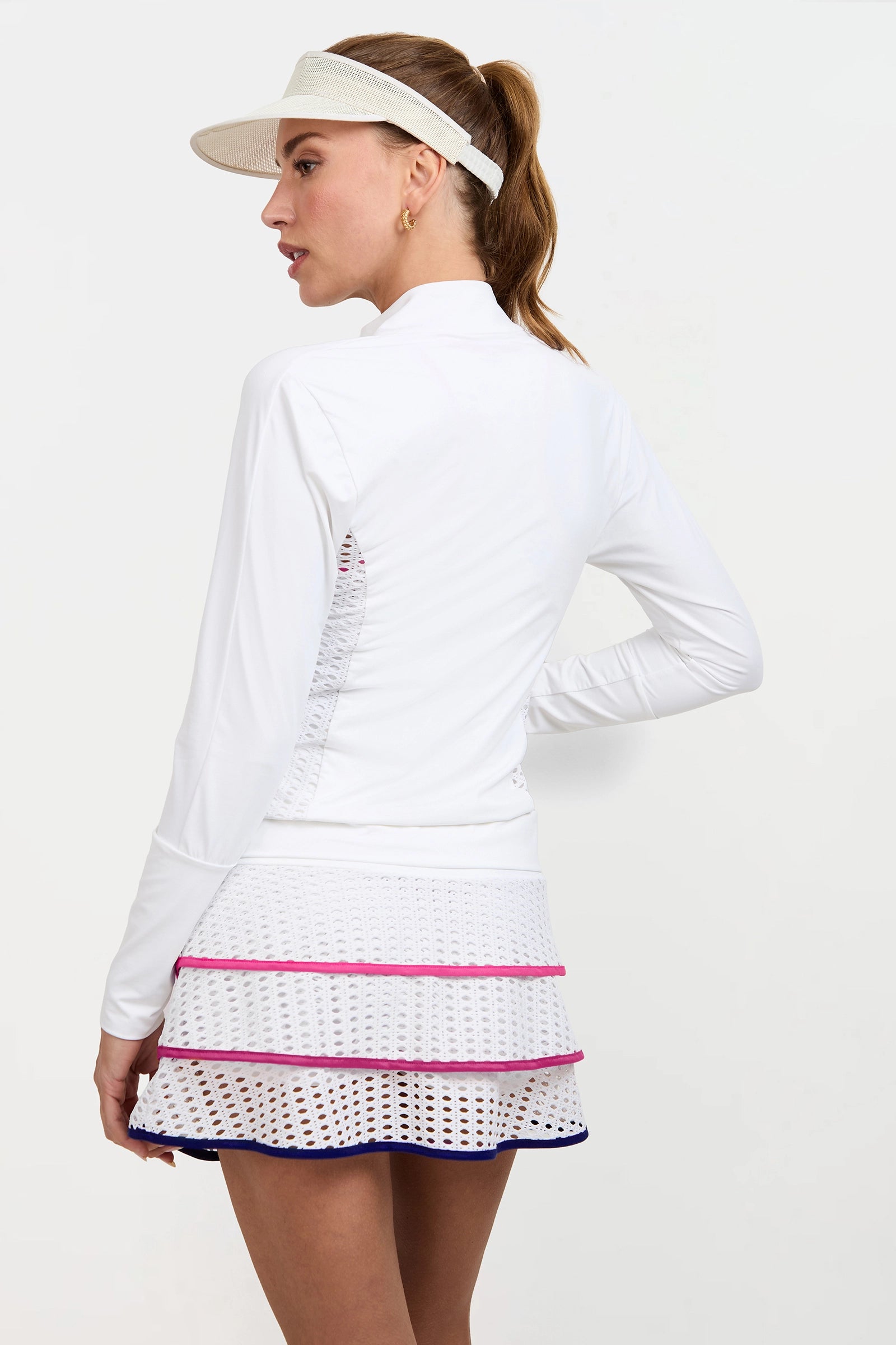 A woman wearing the Performance Jacket stands with her back slightly turned, looking to the side against a plain background.