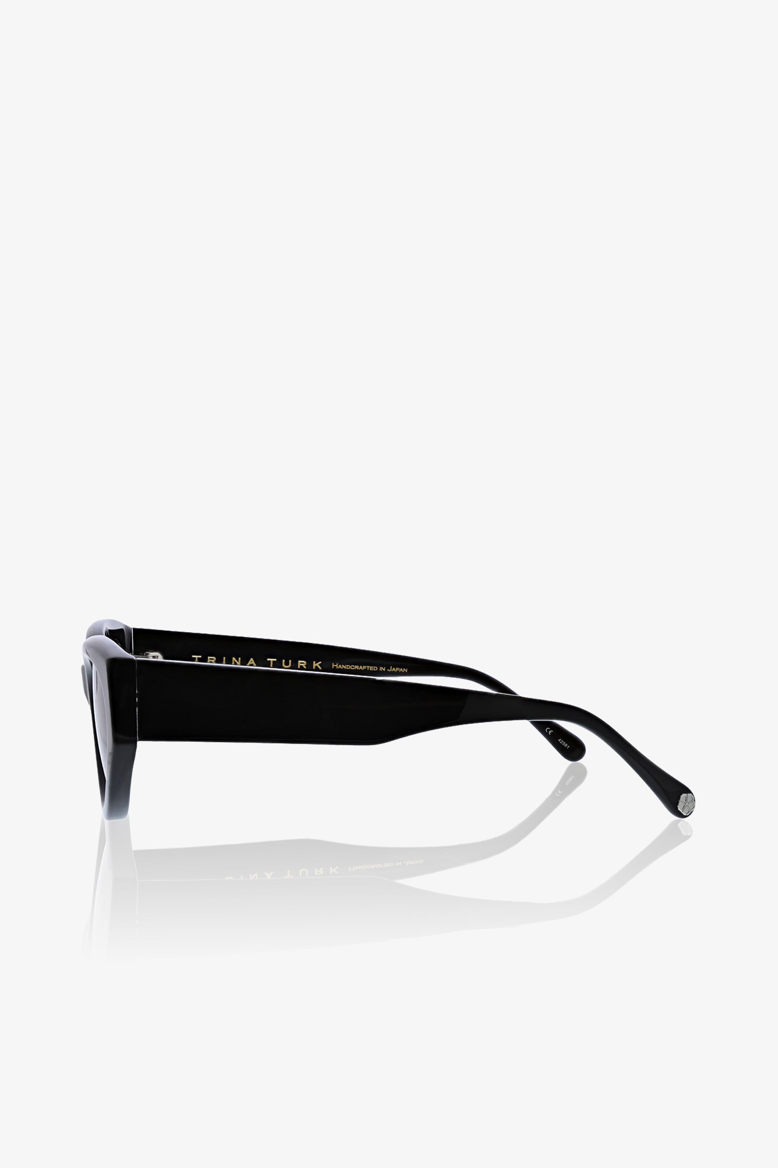 The Boulders Sunglass is displayed from a side angle, featuring a black rectangular frame with thick arms and a subtle gold inscription on the inner arm, set against a plain white background.