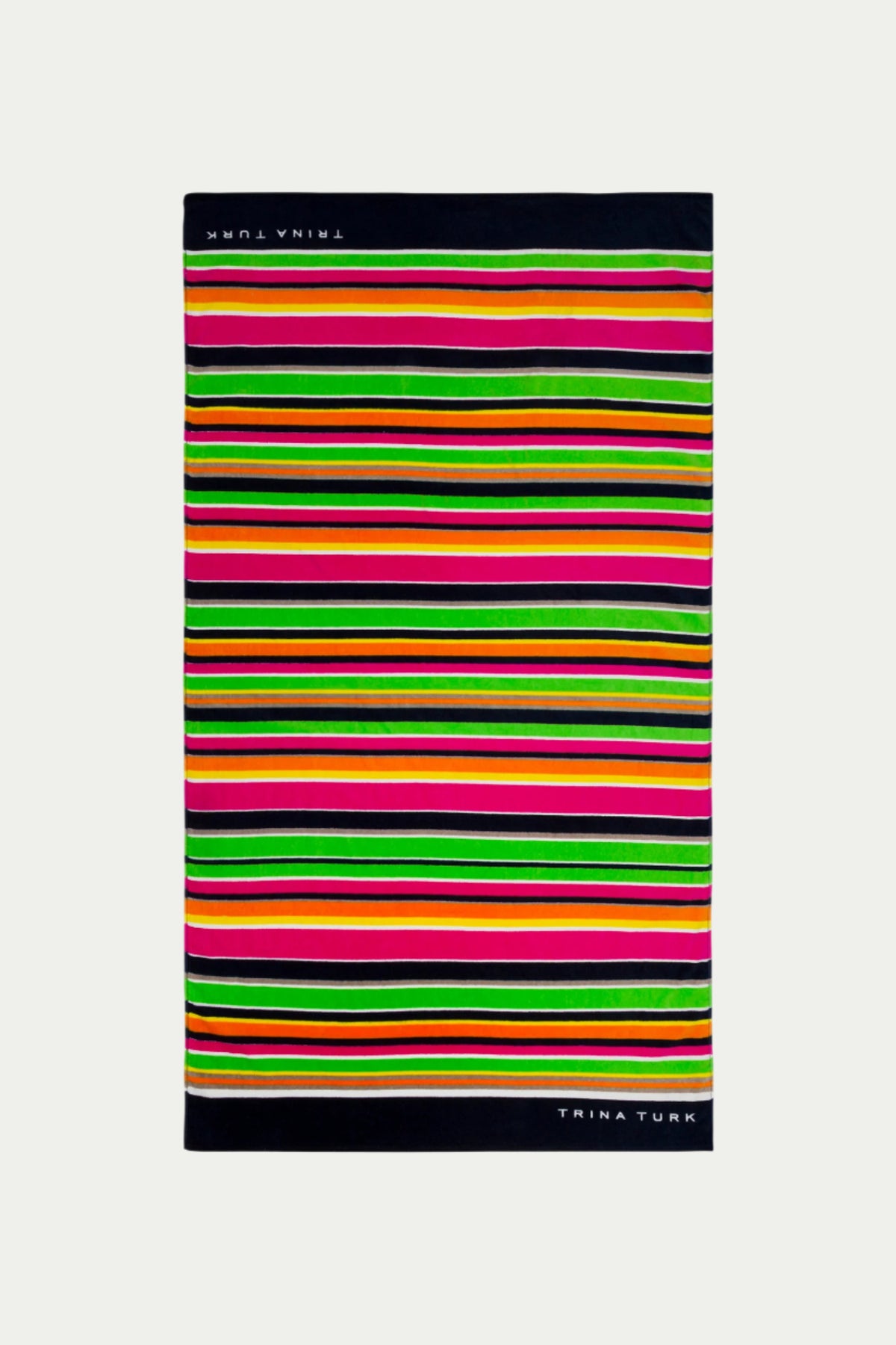 The TT Anniversary Stripe Terry Cloth Towel features multi-colored horizontal stripes in bright shades, black borders, and TRINA TURK in white on opposite edges.