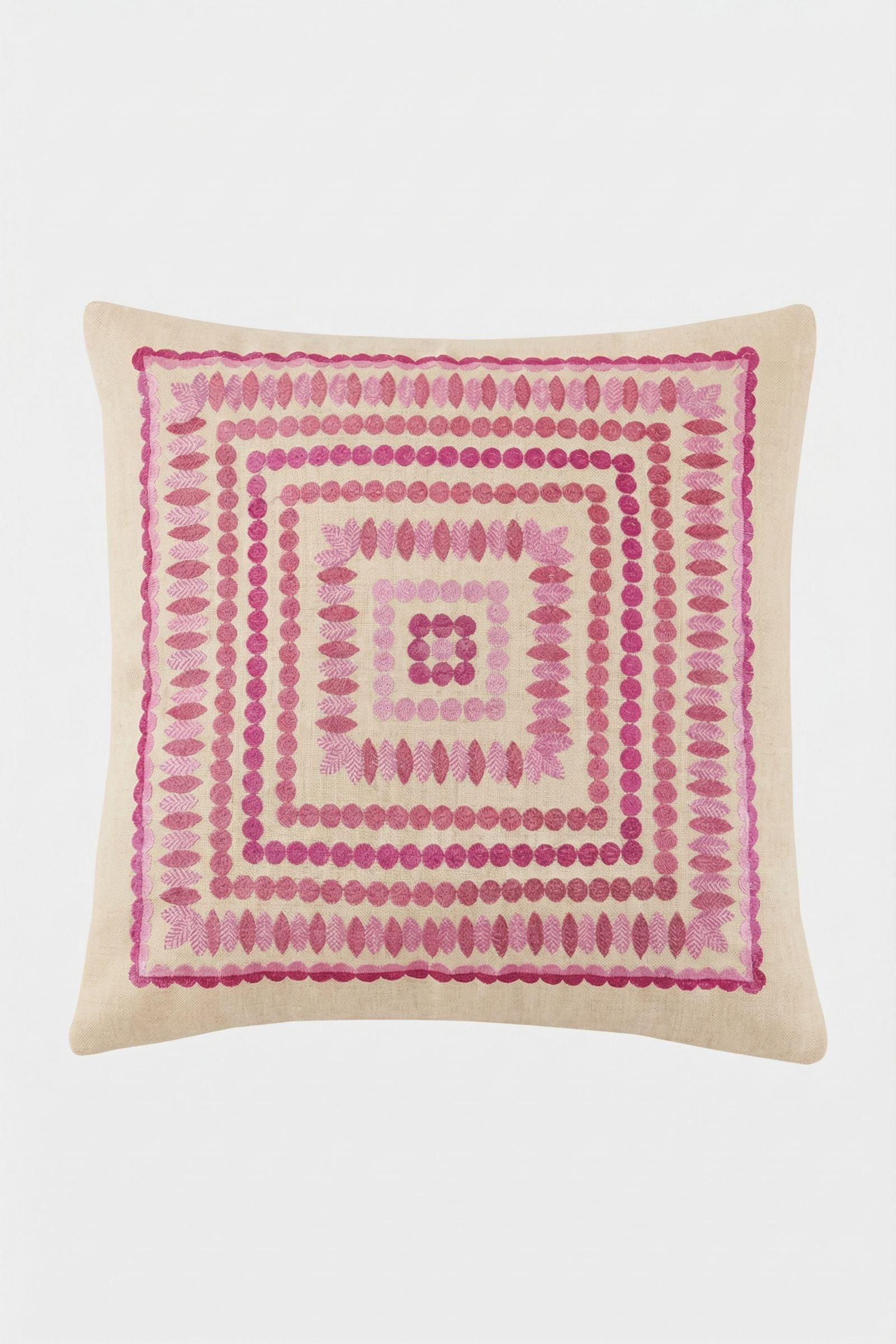 The Carmel Embroidered Pillow 20x20" features a beige base with pink geometric embroidery—concentric squares, circles, and leaf motifs—creating a symmetrical, decorative accent for your space.