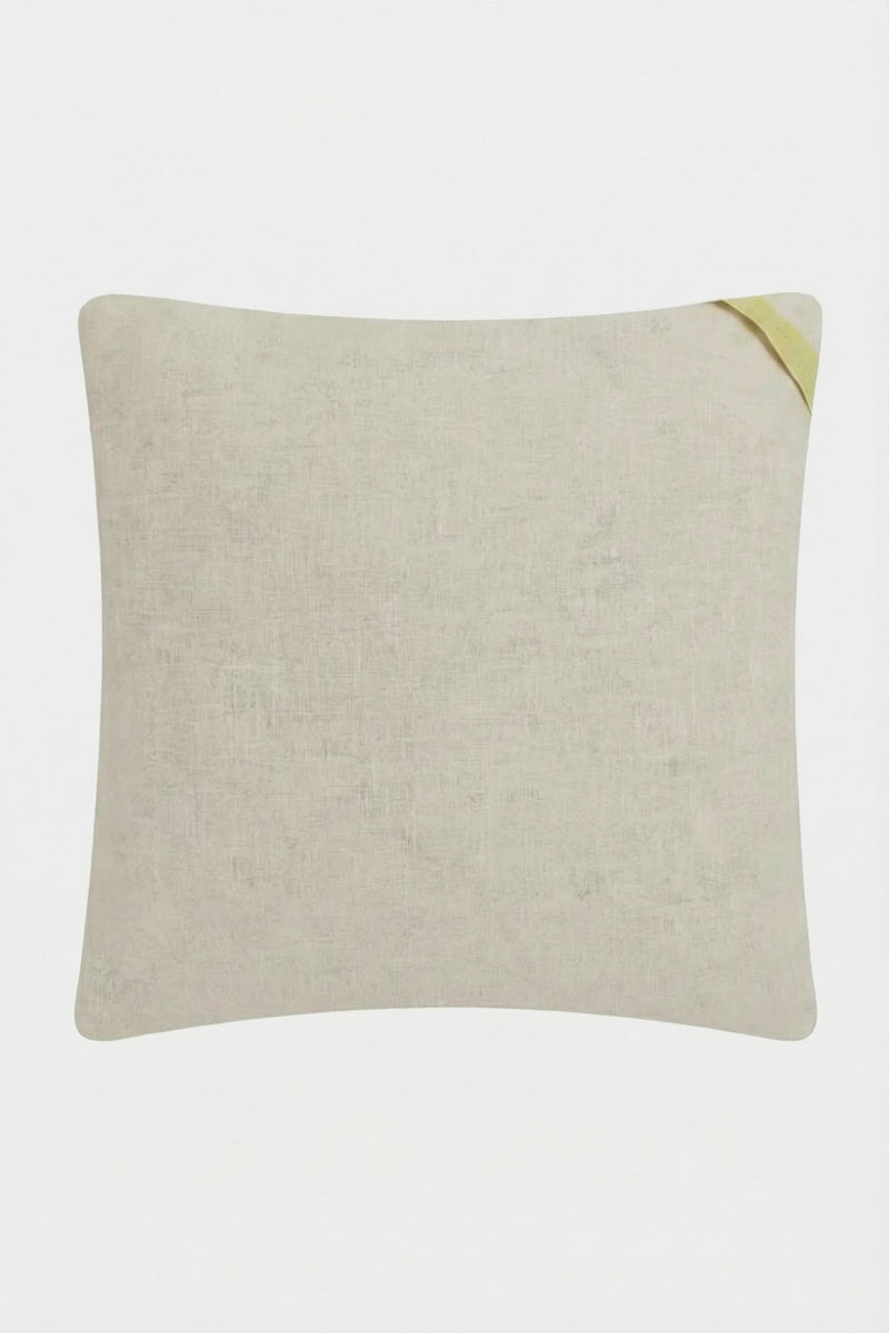 The Costa Mesa Embroidered Square Pillow is a light beige, rectangular cushion with a subtle textured pattern and a small diagonal yellow fabric loop at one corner, shown on a plain white background.