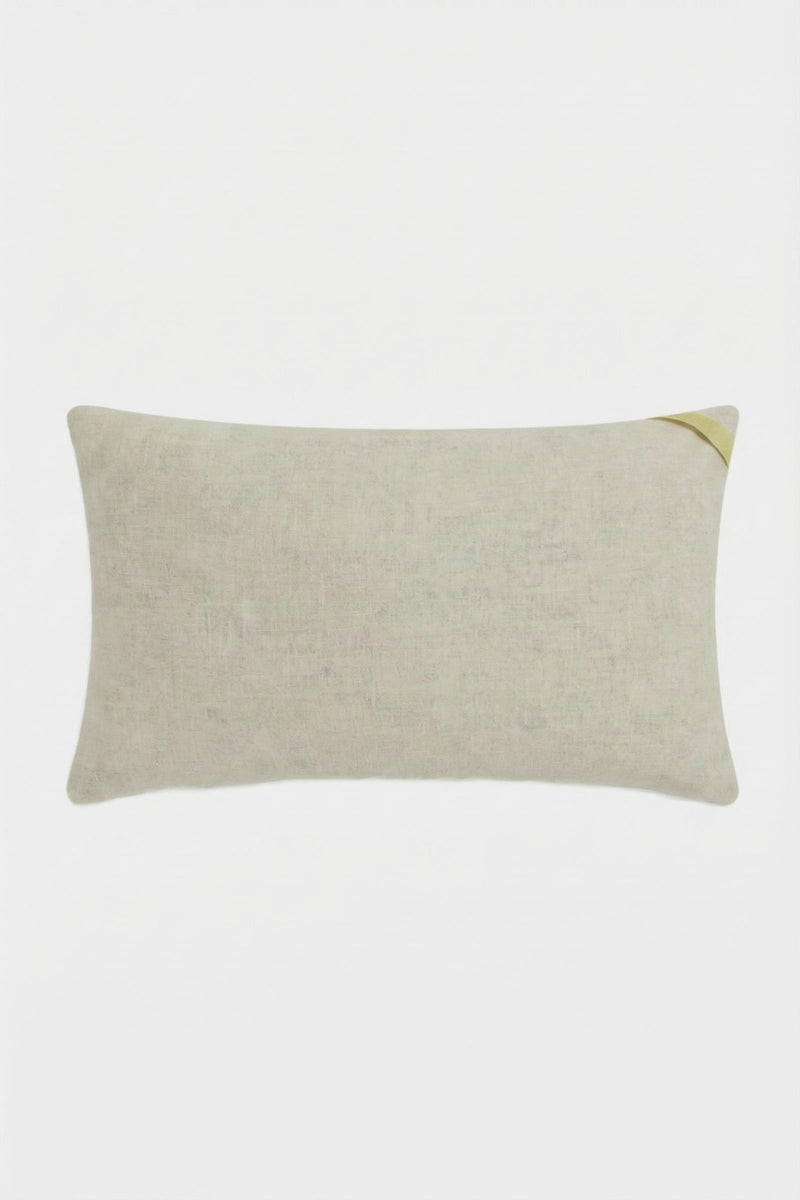 The Escondido Embroidered Lumbar Pillow is rectangular and beige, featuring a subtle textured fabric and a small diagonal gold accent on one corner, shown against a plain white background.