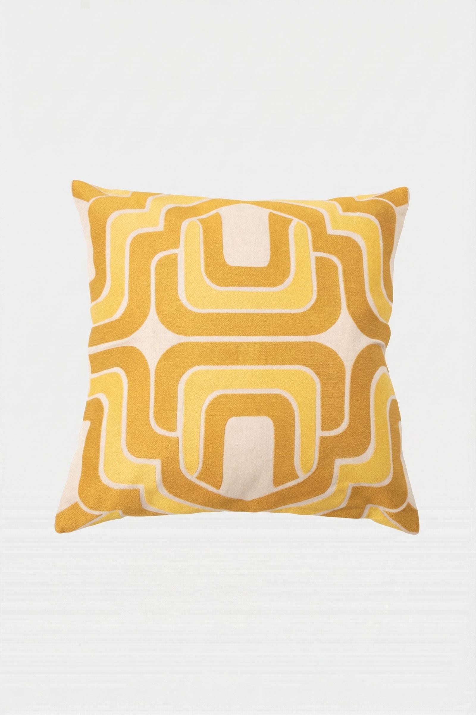 The Ogee Amber Embroidered Square Pillow features a retro geometric pattern in mustard yellow and white, with curved lines and arches forming a symmetrical design on a plain white background.