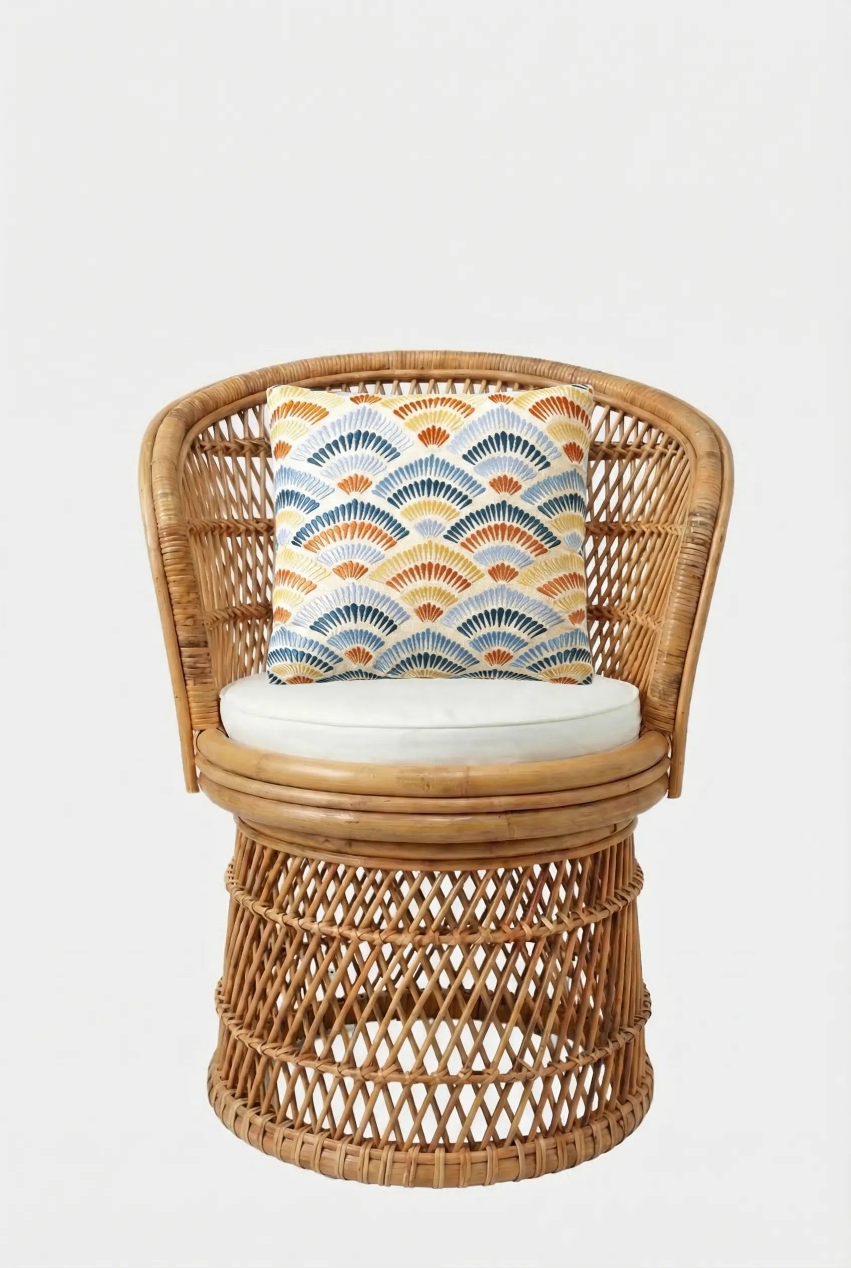 A rattan swivel chair with a white cushion and the Pasadena Embroidered Throw Pillow, which features a blue, orange, and yellow fan pattern, set against a plain white background.