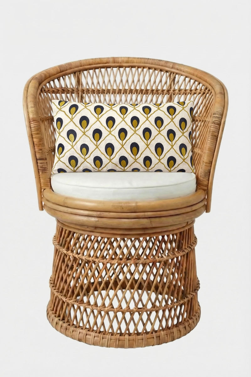 A round rattan chair with a white seat cushion and the Roseville Embroidered Lumbar Pillow, showcasing a yellow, black, and gray geometric pattern, set against a plain white background.