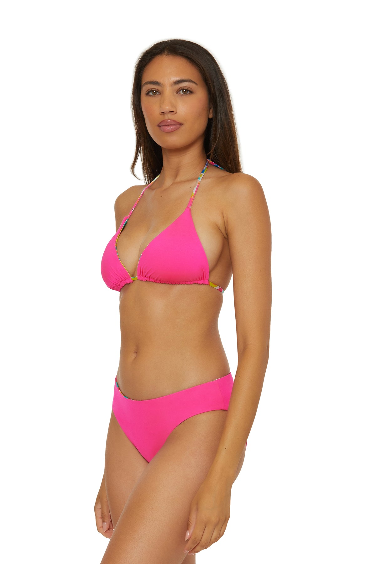 A woman with long brown hair and a neutral expression models the Venus Reversible Hipster Swim Bottom in bright pink, posing slightly to the side against a plain white background.