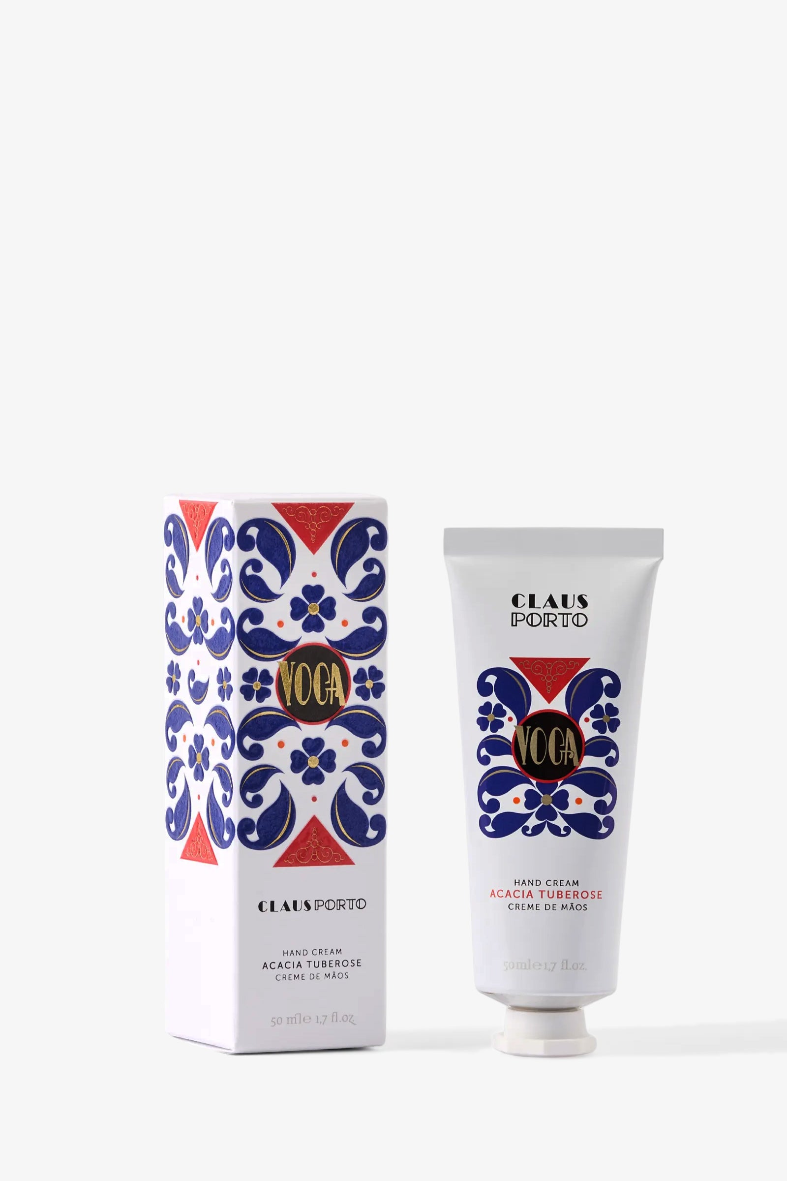 A white tube of Claus Porto Voga Hand Cream and its matching box, both adorned with blue floral patterns and red and gold accents, are displayed on a plain light background.