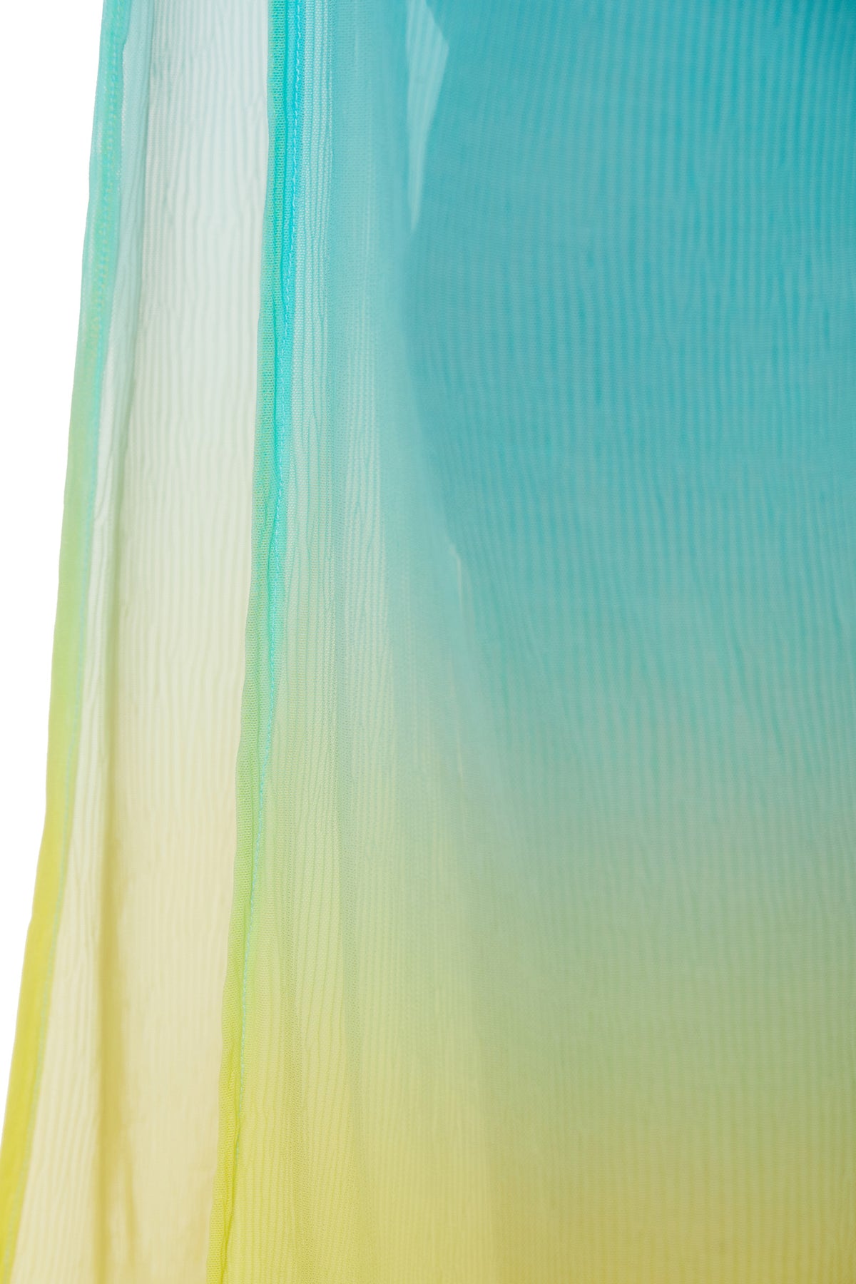 The Pareo Swim Cover-Up - West Palm features translucent fabric with a gradient from yellow at the bottom to blue at the top, showcasing soft folds and a delicate texture against a white background.
