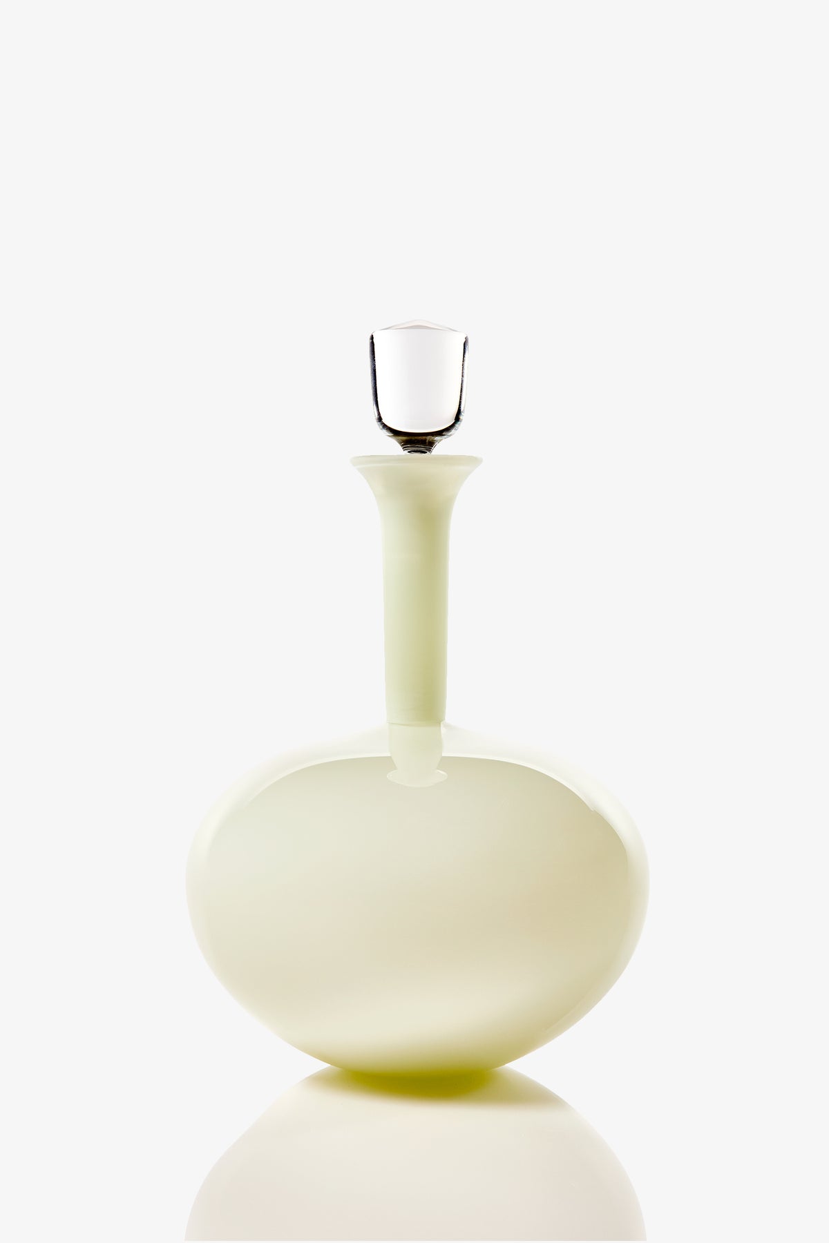 The Wexler Low Oval Bottle is a round, pale glass decanter featuring a long neck and a clear glass stopper, shown against a plain white background.