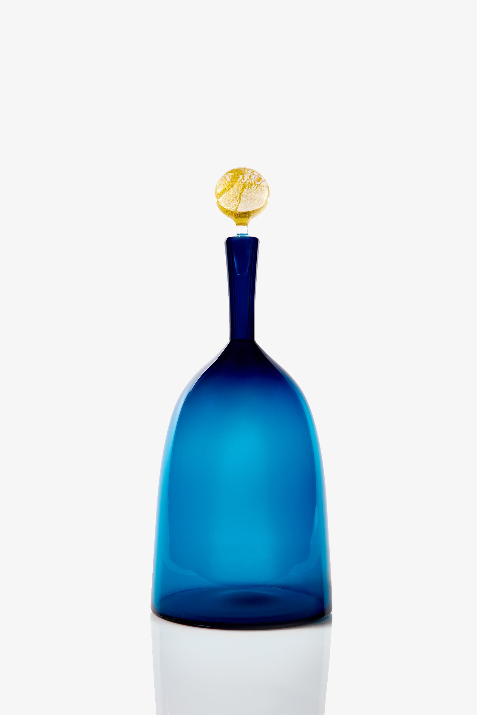 The Wide Bottle Carmella Barware features a blue glass design with a tall, slender neck and a decorative yellow stopper, showcased against a plain white background.