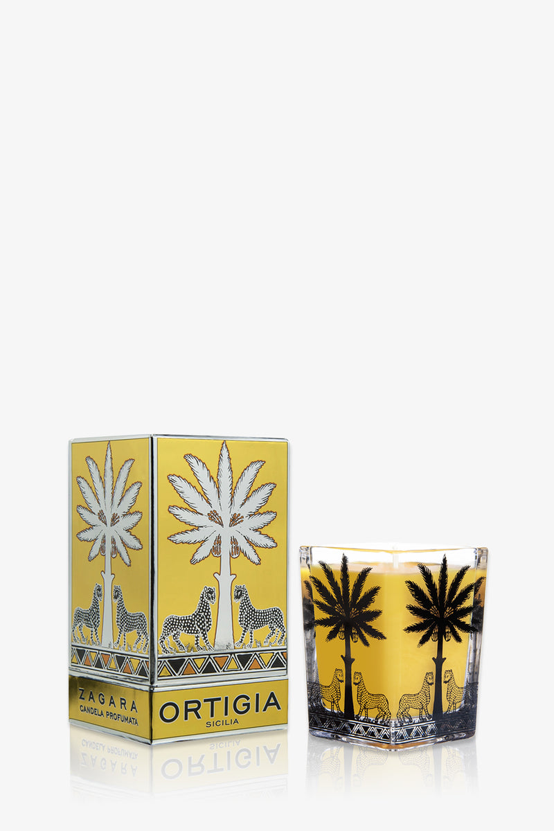 A yellow Ortigia Candle Large Square sits beside its matching box, both decorated with black palm trees and leopard designs with silver details on a yellow background.
