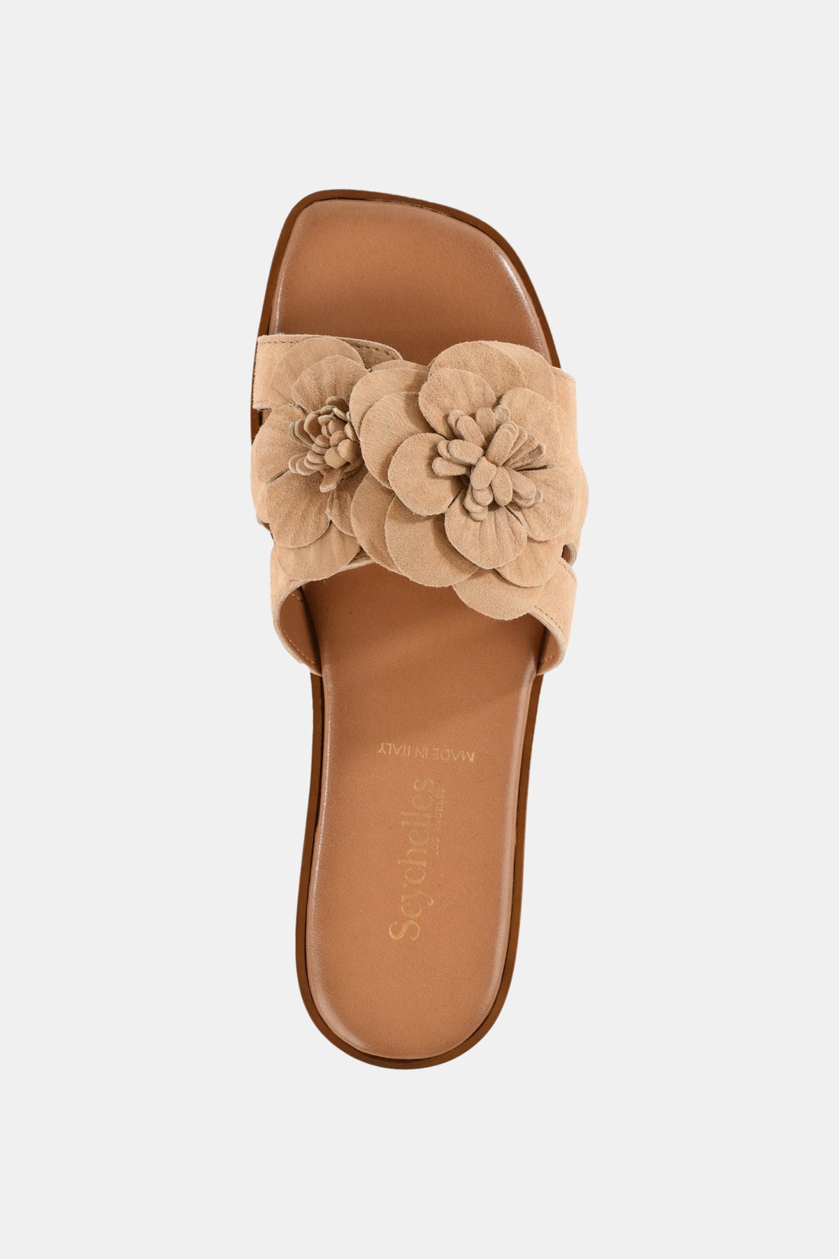The Seychelles Morning Dew Slide is a tan sandal with a wide strap adorned with layered floral accents, a brown footbed, and an open toe, shown from above on a plain white background.