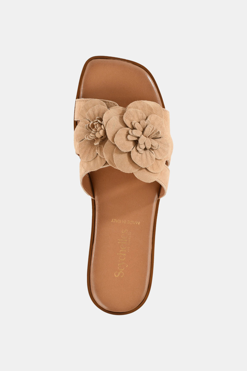 The Seychelles Morning Dew Slide is a tan sandal with a wide strap adorned with layered floral accents, a brown footbed, and an open toe, shown from above on a plain white background.