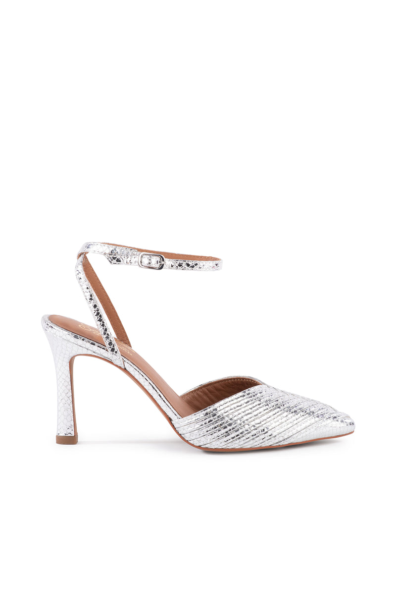 The On To The Next Strappy Silver Heel With Pointed Toe features a metallic silver color, textured snakeskin-like pattern, ankle strap with buckle, and a moderately high flared heel for an elegant touch.