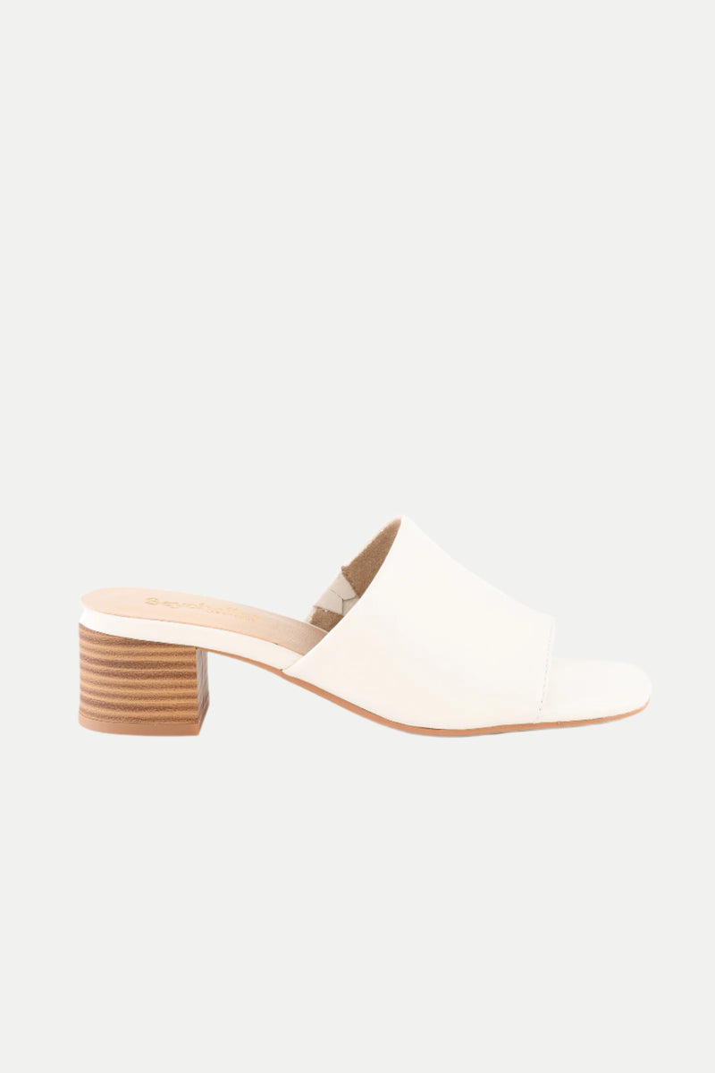 The Pepper White Leather Heeled Mule Sandal features an open toe, wide strap, and low stacked wooden block heel in white leather, displayed in profile against a plain white background.