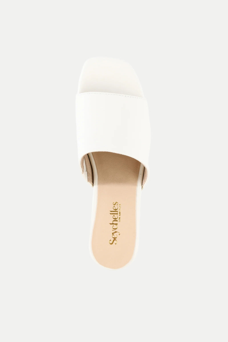 The Pepper White Leather Heeled Mule Sandal features a single wide strap, a beige insole, and the Seychelles logo, shown from a top-down view against a plain background.