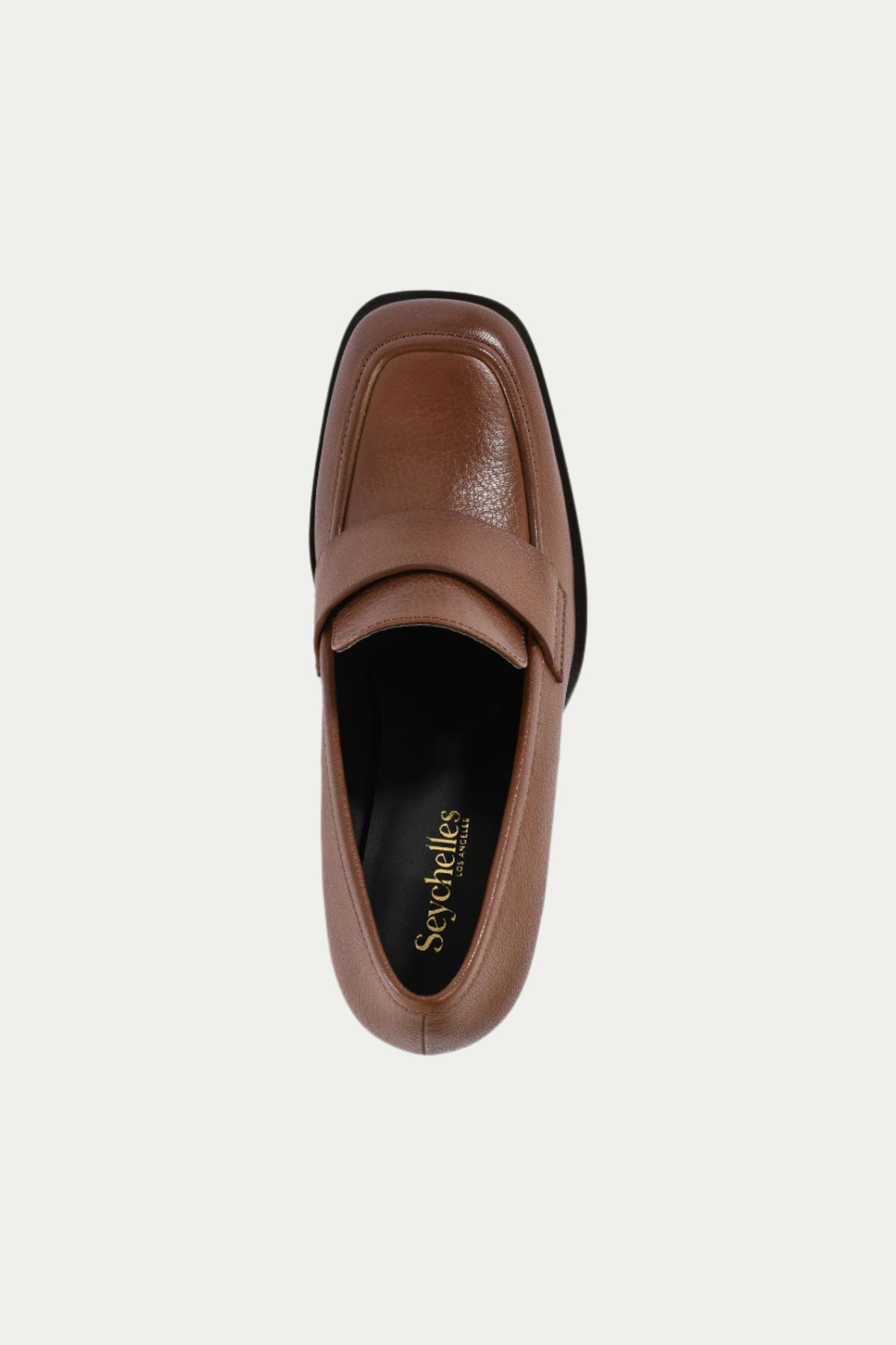 Top view of the Run The World Brown Leather Heeled Loafer featuring a cushioned black insole with gold Seychelles branding, a strap across the square toe, and brown leather construction.